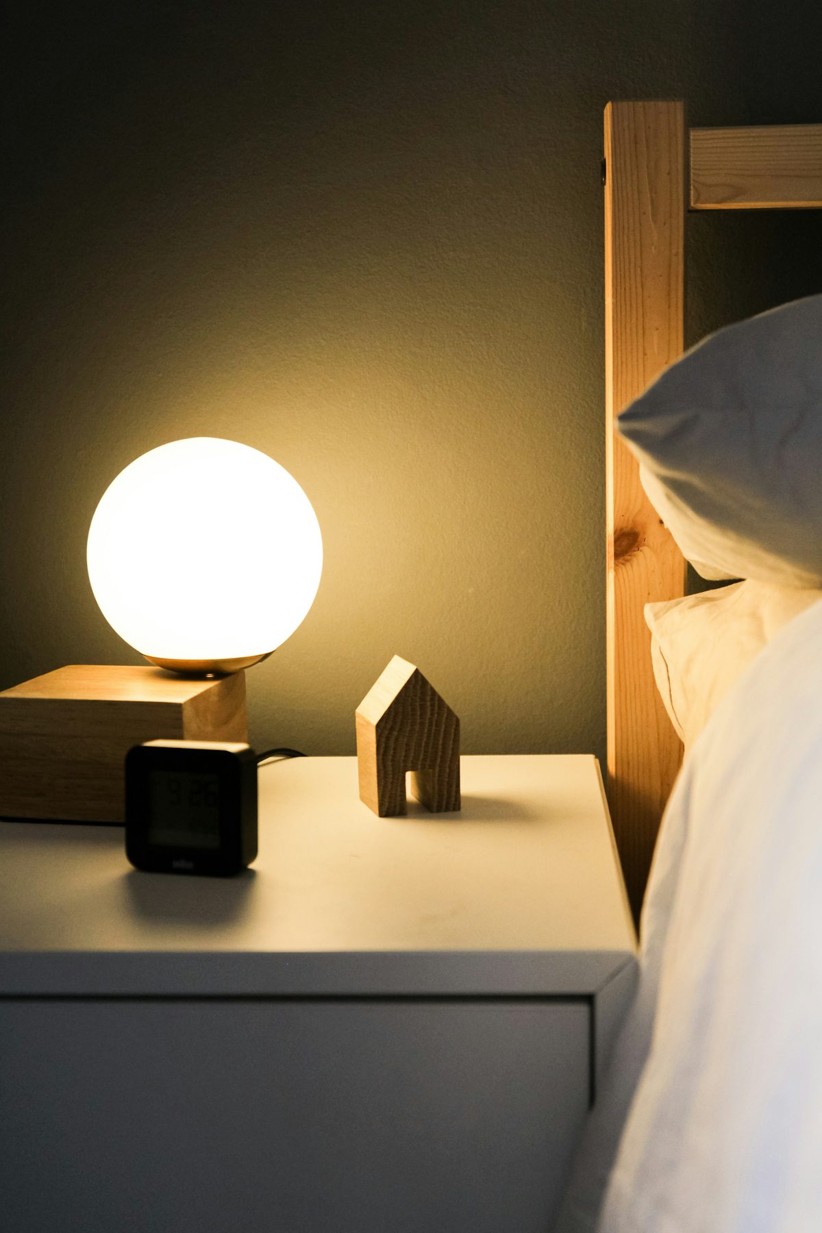 A Hatch Restore 3 sunrise alarm clock glowing softly on a wooden bedside table
